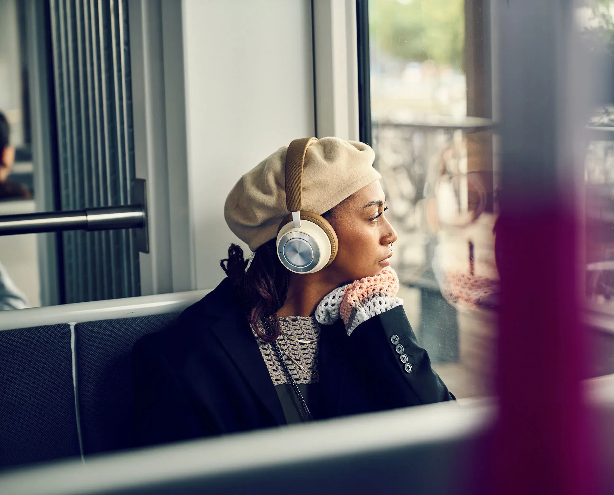 Moški posluša glasbo z brezžičnimi slušalkami DALI IO-8 s tehnologijo za odpravljanje šumov